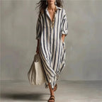 Woman walking in a blue striped maxi shirt dress with collar, V-neck, long sleeves and a woven tote bag