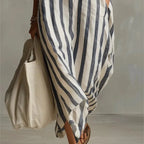 Close-up of the asymmetric hem and flowing fabric of the blue striped maxi dress near the ankles