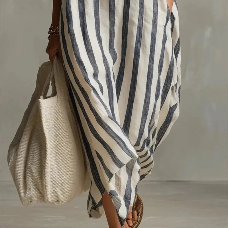 Close-up of the asymmetric hem and flowing fabric of the blue striped maxi dress near the ankles