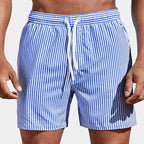Front view of man wearing blue and white vertical striped boardshorts with white drawstring waist.