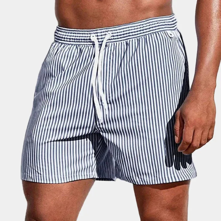 Close-up front view of navy and white striped boardshorts with button tab waist detail.