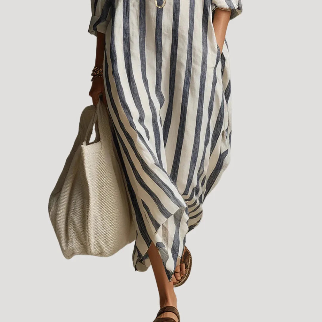 Close-up of the flowing hemline and side pocket detail on the blue and white striped maxi dress