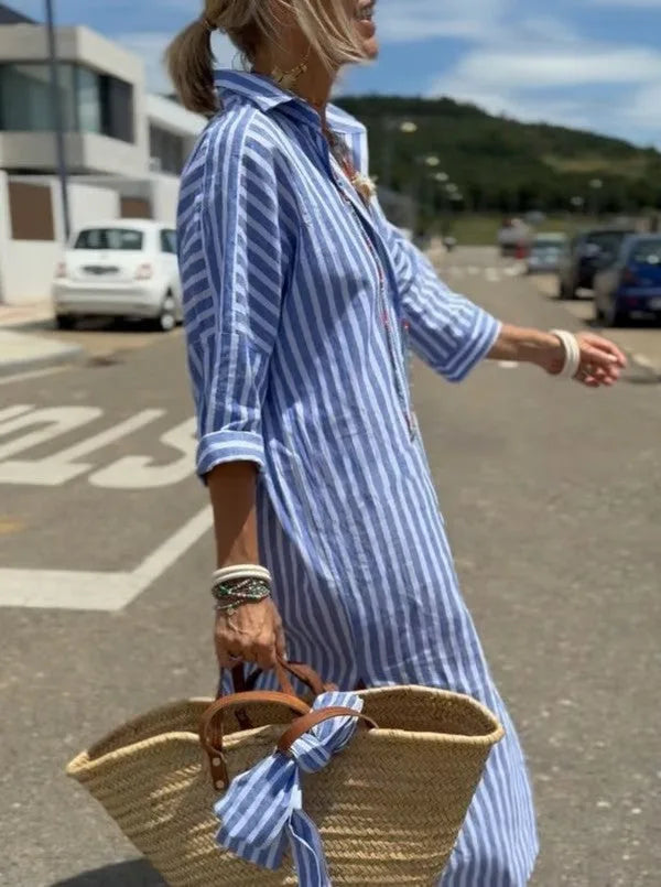Side view of woman in blue and white striped midi shirt dress with rolled 3/4 sleeves, carrying a woven straw tote