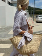 Close-up of blue and white striped cotton shirt dress with collar and button placket, worn with crossbody bag