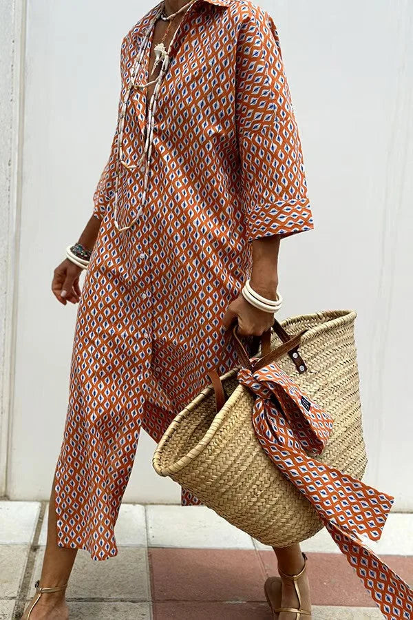 Woman walking in orange and blue geometric print midi shirt dress with rolled sleeves and straw tote bag