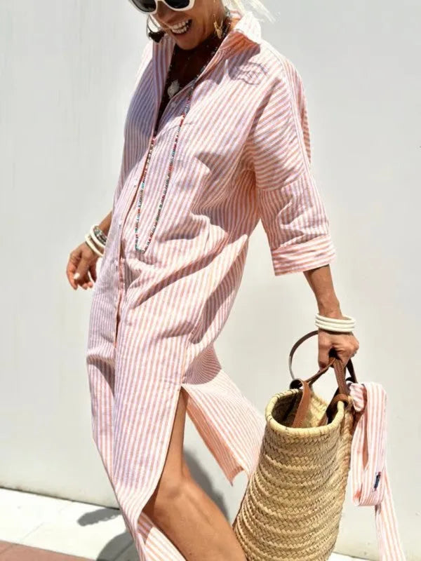 Woman in bright flash of coral and white striped shirt dress walking with woven tote bag