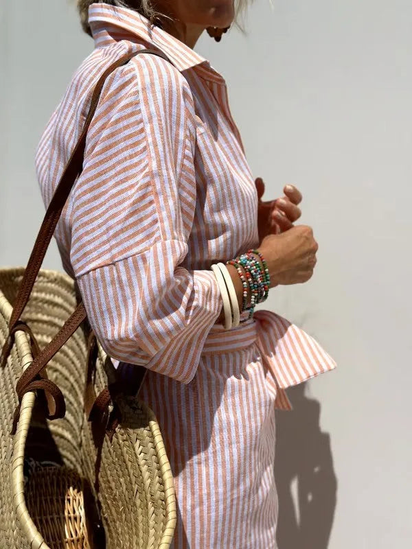 Close-up of coral and white striped linen-blend fabric with rolled sleeve cuff and tied waist detail