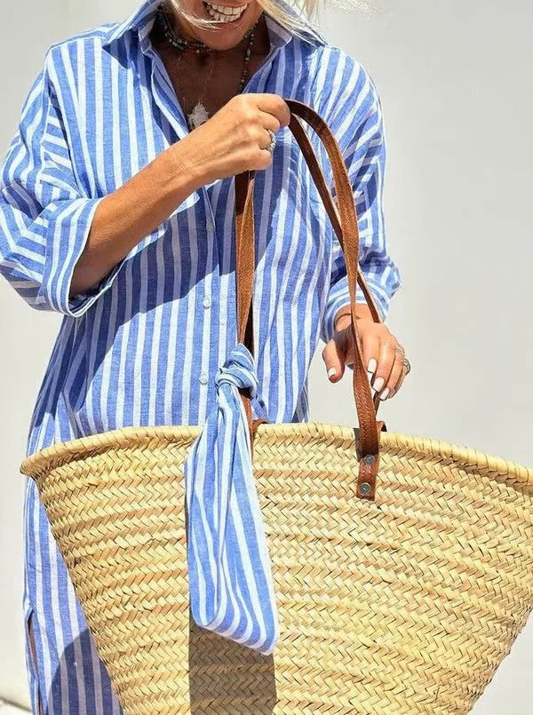 Full front view of pink and white striped collared shirt dress with button placket and straw tote
