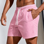 Side view of pink and white striped boardshorts with hand resting in the side pocket