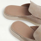Front-angled view of a grey suede slip-on mule displaying the low-profile silhouette and white outsole