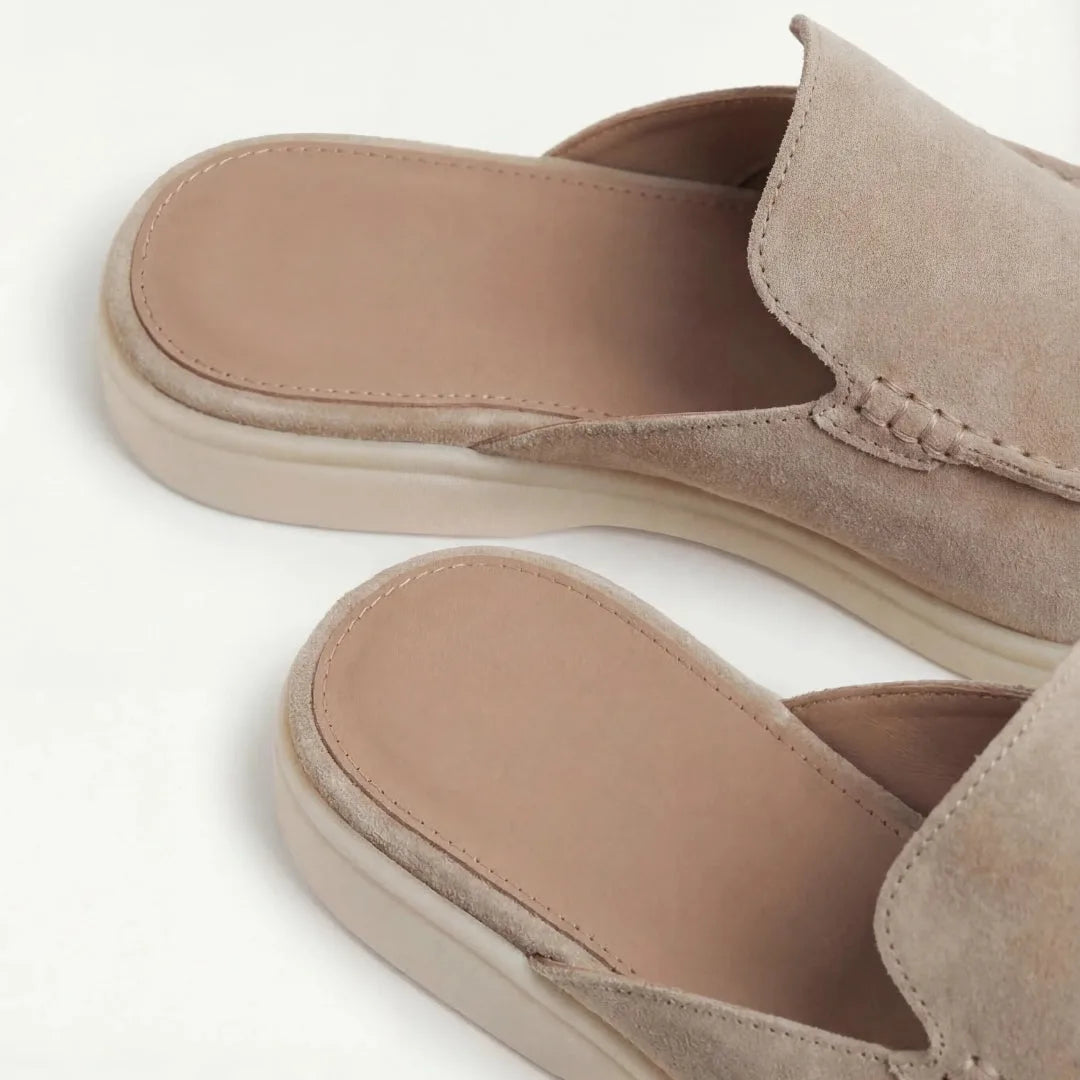 Front-angled view of a grey suede slip-on mule displaying the low-profile silhouette and white outsole