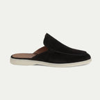 Side profile of a black suede slip-on mule with closed toe, open back and contrasting cream sole