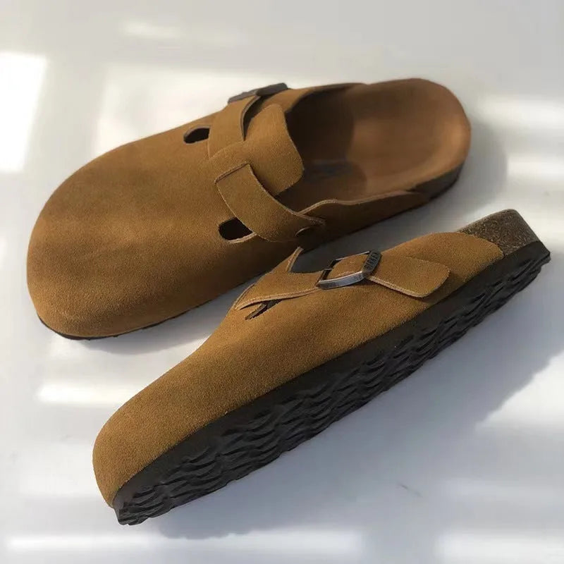Top and side view of brown suede clog slippers with buckle strap and cutout detail, cork midsole and dark sole
