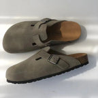 Pair of grey suede buckle clogs shown from above and the side, with soft tan footbed and cork trim