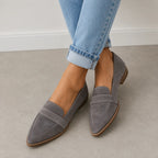 Front view of grey suede pointed-toe loafers worn with cuffed jeans, showing the penny strap and tan outsole