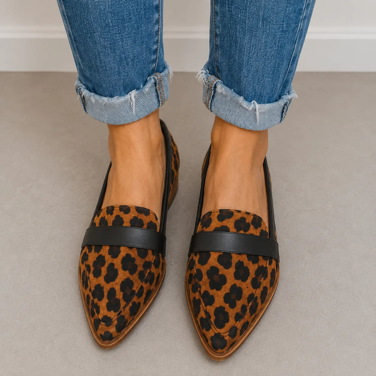 Front-facing pair of leopard-print pointed-toe loafers with a black leather penny strap and black trim