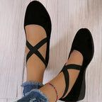 Overhead view of black suede ballet flats with crisscross elastic straps across the instep and a low wedge heel