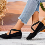 Side profile of black suede crisscross ballet flats paired with cropped frayed-hem jeans