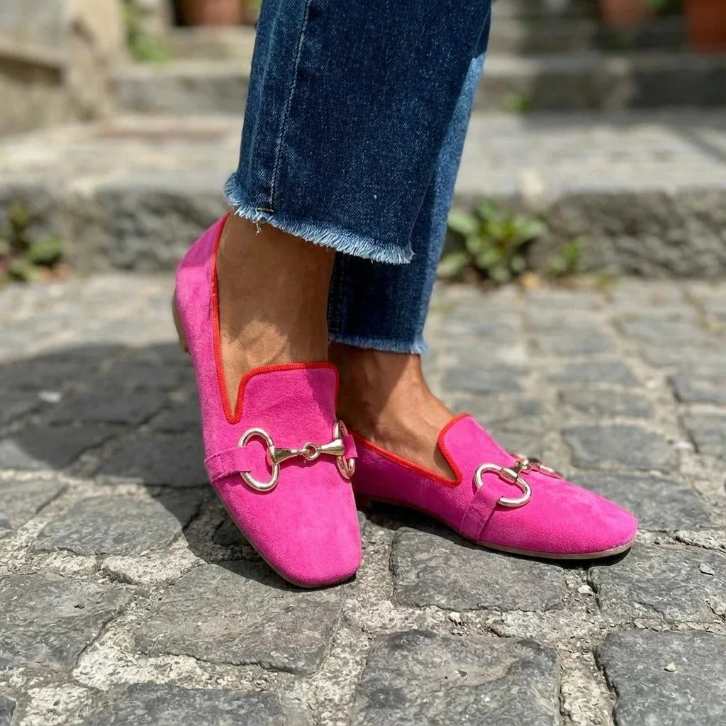 Side profile of pink suede loafer showing the gold horsebit buckle detail and contrasting red trim at the collar