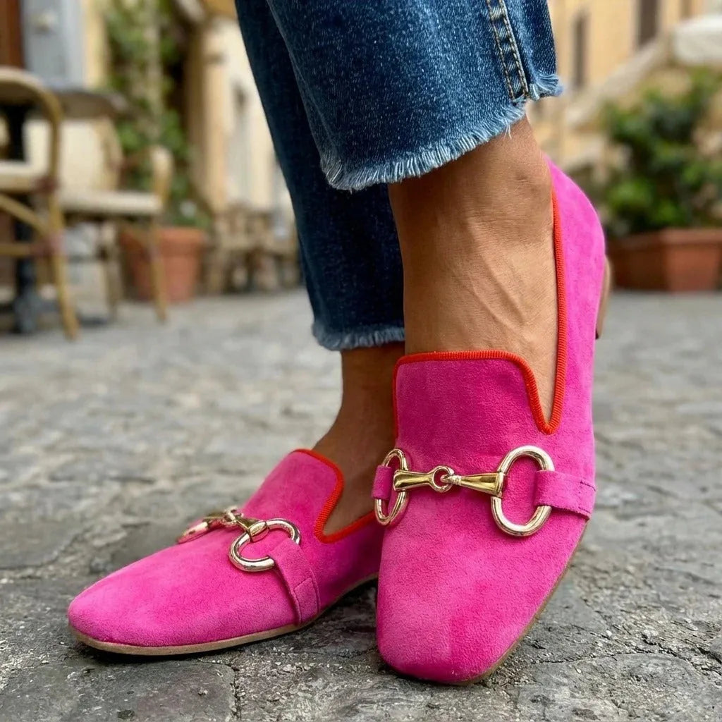 Close-up of red piped collar on a pink suede loafer, highlighting the colour-block trim and gold buckle strap