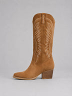 Side profile of a single tan suede cowboy boot, highlighting the pointed toe and stacked wooden-look heel