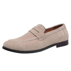 Beige suede penny loafer shown from the side, revealing its low heel and tan leather lining