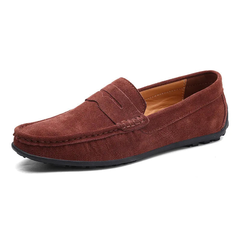 Rust brown suede penny loafer with visible stitched apron toe and flexible driving sole