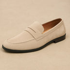 Single beige suede penny loafer with contrast stitching and a slim black sole, shown in side profile