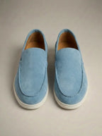Light blue suede slip-on loafers viewed from above, showing soft texture and cream-coloured outsole