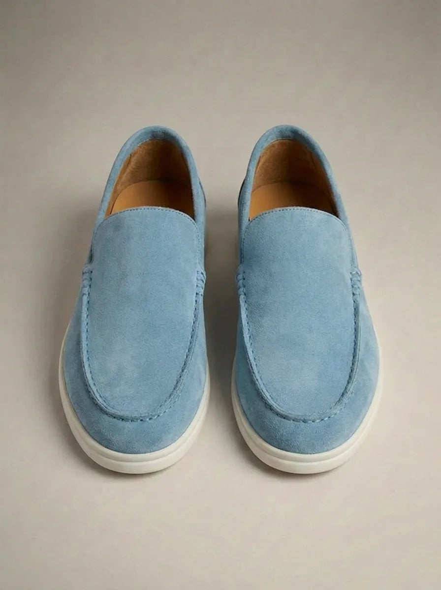 Light blue suede slip-on loafers viewed from above, showing soft texture and cream-coloured outsole