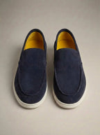 Navy suede slip-on loafers with a striking yellow leather lining, shown from directly above