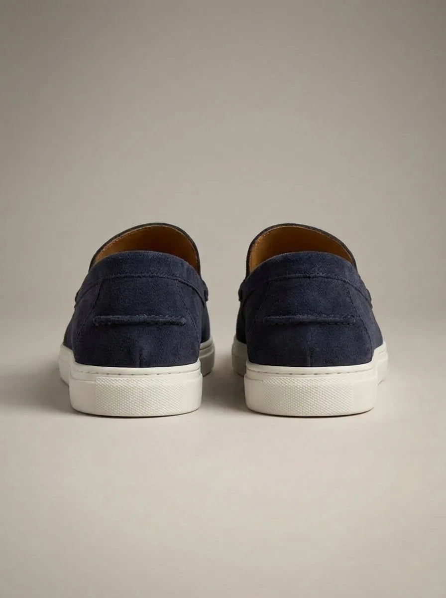 Rear view of navy suede slip-on loafers showing the heel seam, white outsole and low-profile silhouette