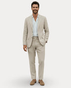 Front view of a man wearing a beige linen suit with a light blue shirt and suede loafers