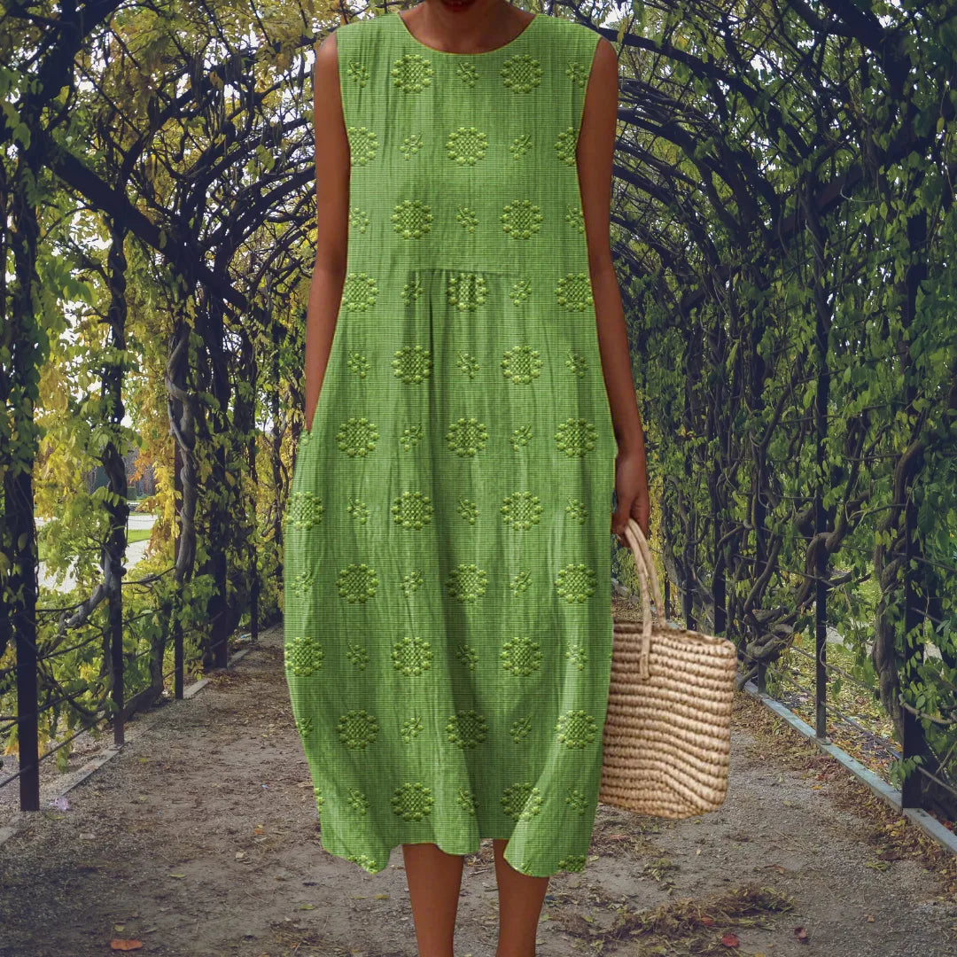 Green sleeveless midi dress with raised dot pattern, shown from the front under a leafy garden archway.