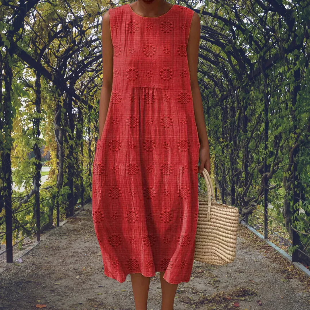 Red sleeveless midi dress with embossed dot detailing, paired with a woven handbag for a casual look.