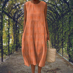 Orange sleeveless midi dress with raised circular motifs, showing the crinkled cotton texture up close.