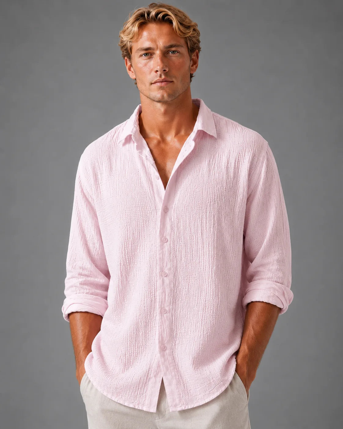 Man wearing a pink textured cotton shirt with collar open, untucked, paired with beige pants, front view