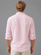 Back view of pink textured cotton shirt showing shoulder seam, rolled sleeves and curved hem