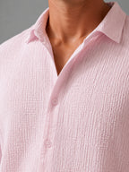Close-up of pink textured shirt collar and button placket showing crinkled cotton weave detail