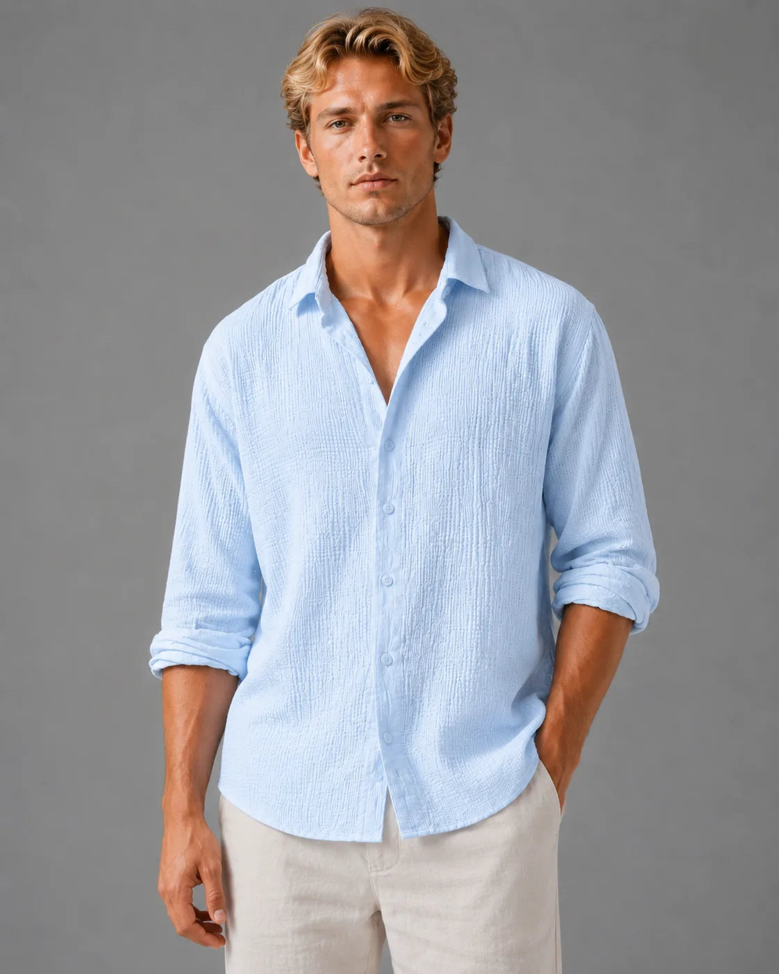 Man wearing a light blue textured cotton shirt, buttoned, with sleeves rolled and collar open