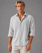 Man wearing a light grey textured cotton shirt, front view, buttoned with rolled sleeves