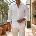 Model in a crisp white long-sleeve shirt with rolled cuffs, open collar, styled with cream trousers