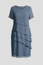 Blue layered chiffon dress on a mannequin, round neckline, short sleeves and asymmetric tiered skirt panels