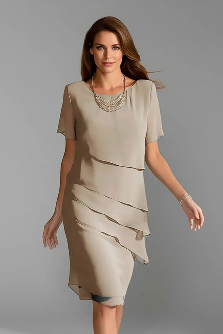 Model wearing a beige tiered chiffon dress with short sleeves, layered necklace and bracelet