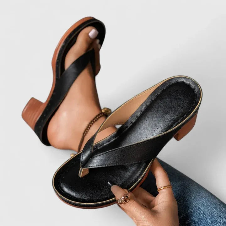 Close-up side view of black leather thong-strap sandal with stacked wood block heel
