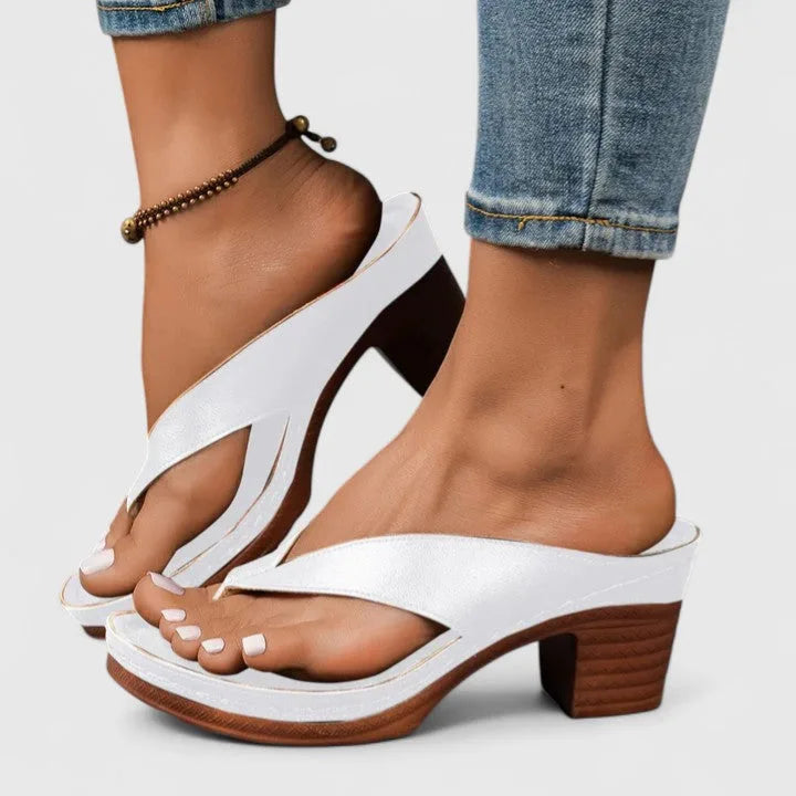 Angled close-up of white sandal highlighting the woven strap detail and dark wood heel