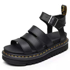 Angled front view of black faux leather platform sandal showing three wide straps and ankle buckle closure