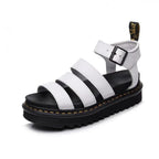 White platform sandal with triple front straps, silver buckle and black sole, shown at an angle