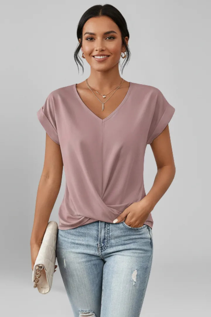 Model wearing a dusty mauve V-neck top with rolled cap sleeves and a twist knot at the hem, paired with jeans