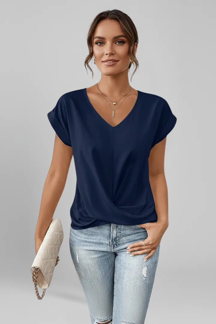 Model wearing a navy blue V-neck top with cap sleeves and a twist-front hem, paired with ripped jeans
